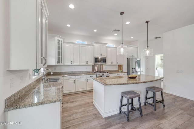 kitchen with white cabinetry, appliances with stainless steel finishes, a sink, and light wood-type flooring