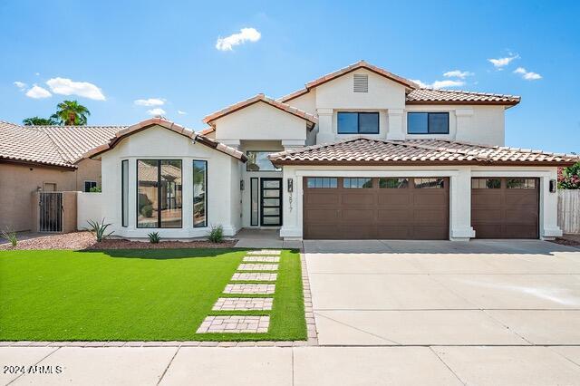 mediterranean / spanish home with a garage and a front lawn