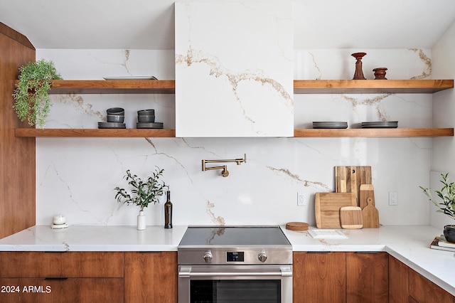 kitchen featuring stainless steel stove, light stone counters, and backsplash