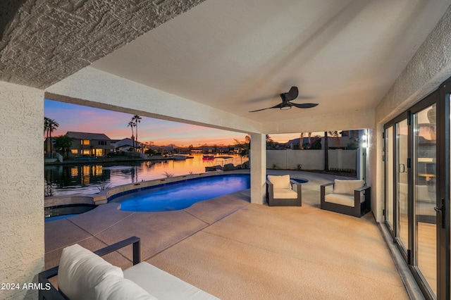 pool at dusk featuring an outdoor hangout area, a water view, ceiling fan, and a patio area