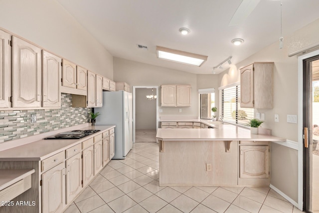 kitchen with tasteful backsplash, white refrigerator with ice dispenser, a peninsula, black electric cooktop, and lofted ceiling