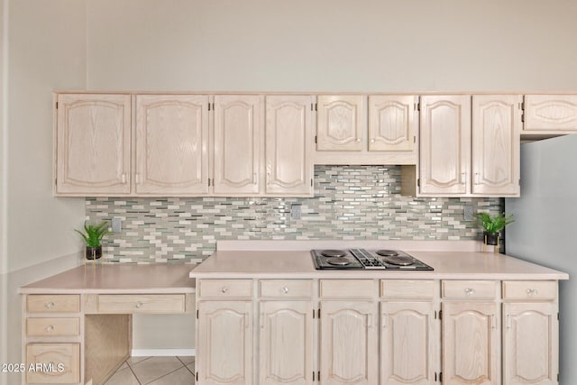 kitchen featuring light tile patterned floors, freestanding refrigerator, decorative backsplash, light countertops, and black electric cooktop