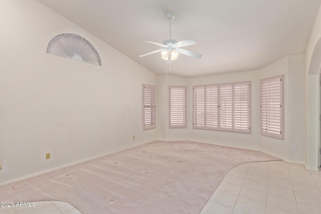 empty room with tile patterned flooring, vaulted ceiling, a ceiling fan, and carpet floors