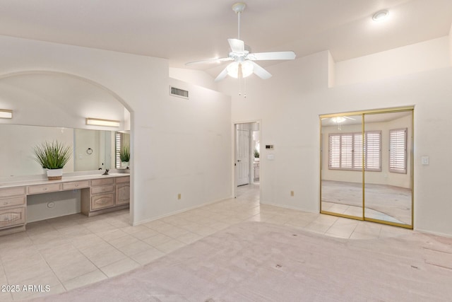 unfurnished bedroom with visible vents, built in desk, a closet, arched walkways, and lofted ceiling