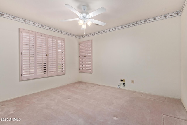 carpeted spare room featuring baseboards and a ceiling fan