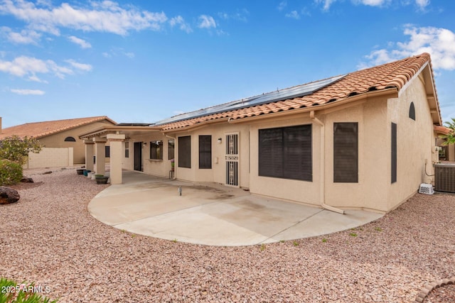 back of house featuring solar panels, a tiled roof, stucco siding, central air condition unit, and a patio area