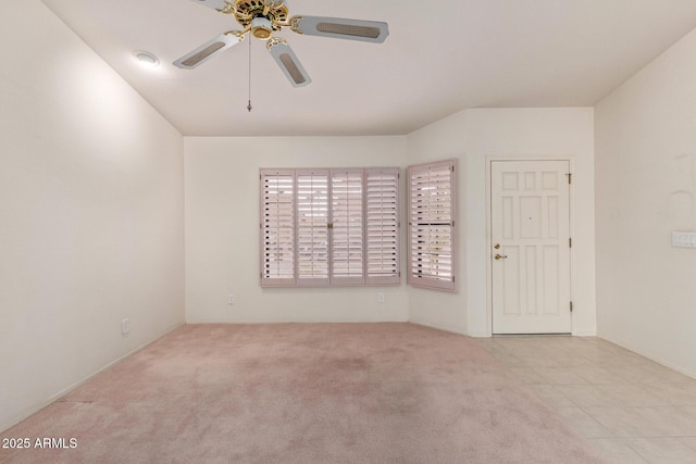 carpeted empty room featuring tile patterned flooring and a ceiling fan