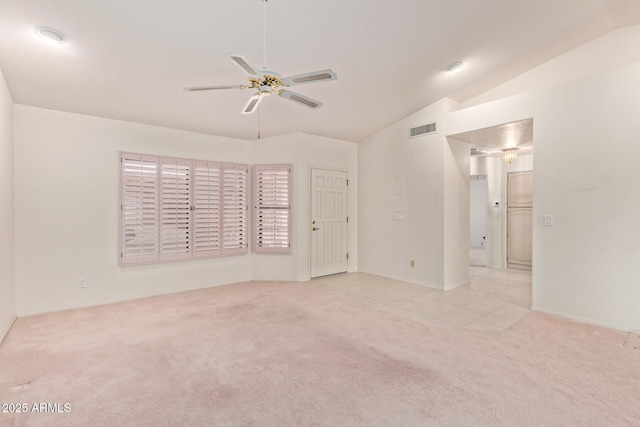 carpeted spare room featuring vaulted ceiling, visible vents, and ceiling fan