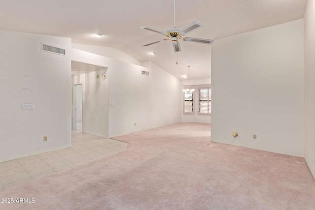 carpeted empty room with visible vents, lofted ceiling, and ceiling fan with notable chandelier