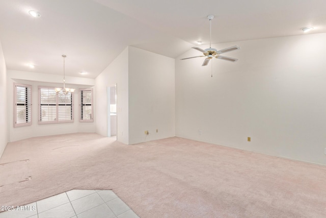 unfurnished living room with ceiling fan with notable chandelier, vaulted ceiling, and light colored carpet