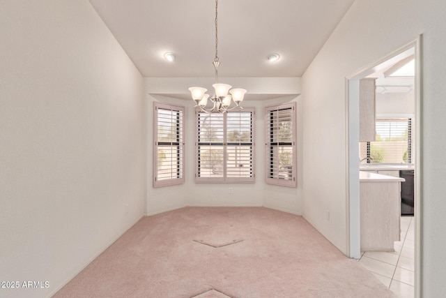 unfurnished dining area with light carpet, a notable chandelier, and plenty of natural light