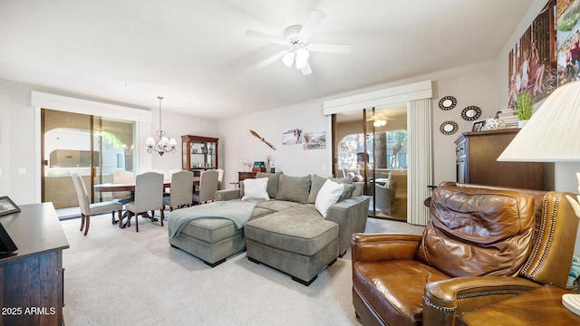 carpeted living room featuring ceiling fan with notable chandelier