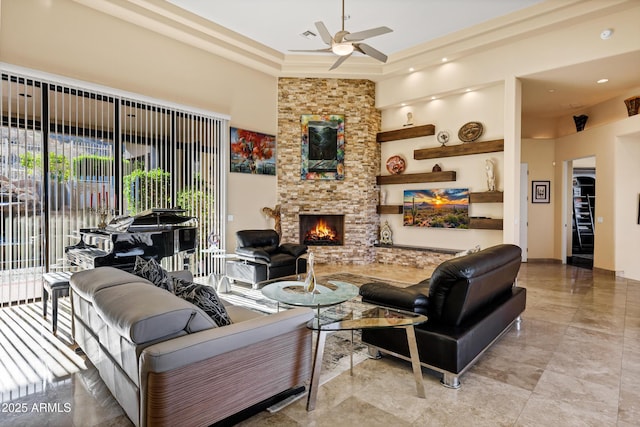 living room featuring a stone fireplace, a towering ceiling, and a ceiling fan