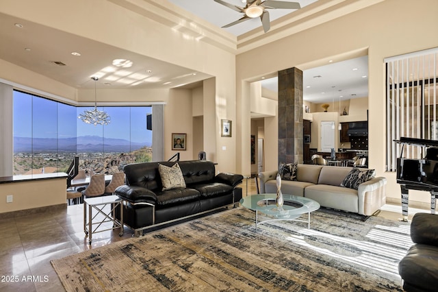 tiled living area with a towering ceiling, ceiling fan, baseboards, and a mountain view