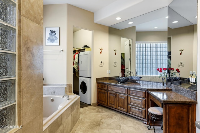 bathroom featuring a walk in closet, recessed lighting, vanity, stacked washing maching and dryer, and a bath