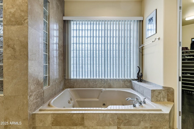 full bathroom featuring a wealth of natural light, a walk in closet, and a tub with jets