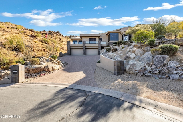 view of front of house with decorative driveway, an attached garage, and stucco siding