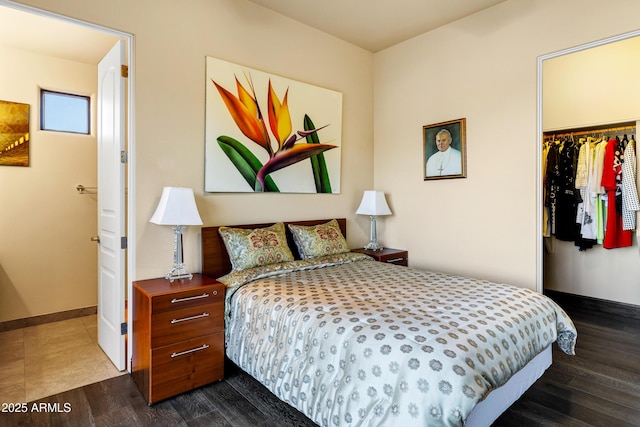 bedroom with a closet, a spacious closet, baseboards, and wood finished floors