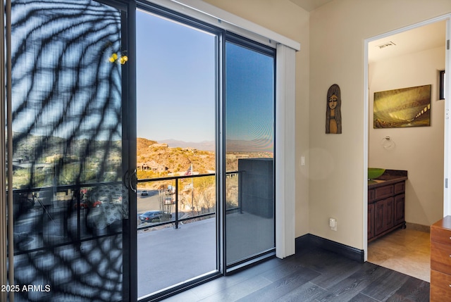 doorway featuring wood finished floors, visible vents, and baseboards