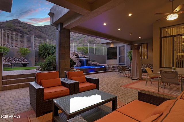 view of patio / terrace with a ceiling fan, outdoor dining space, fence, a mountain view, and an outdoor living space