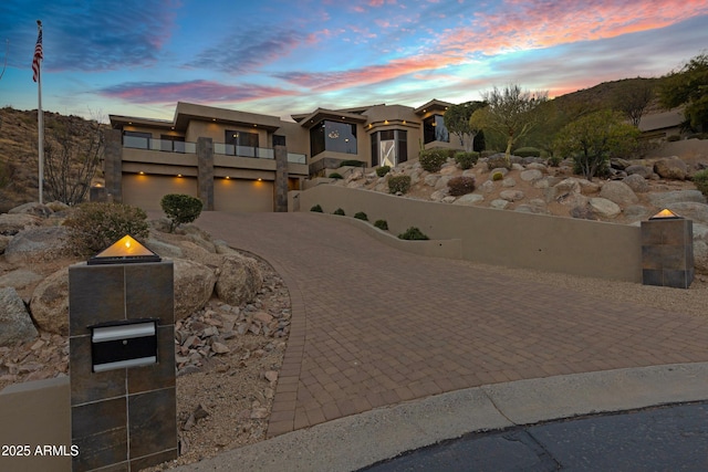 view of front of home with a balcony, decorative driveway, and stucco siding