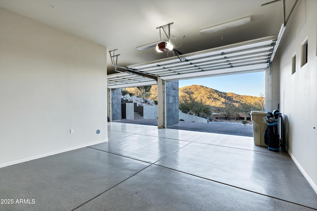 garage featuring a garage door opener, a mountain view, and baseboards