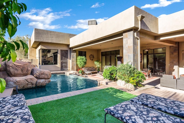 back of house with stucco siding and an outdoor pool