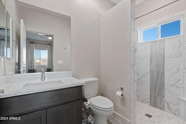 bathroom featuring ceiling fan, toilet, vanity, and tiled shower