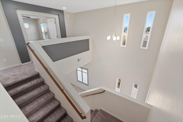 stairway featuring carpet flooring, plenty of natural light, and a chandelier