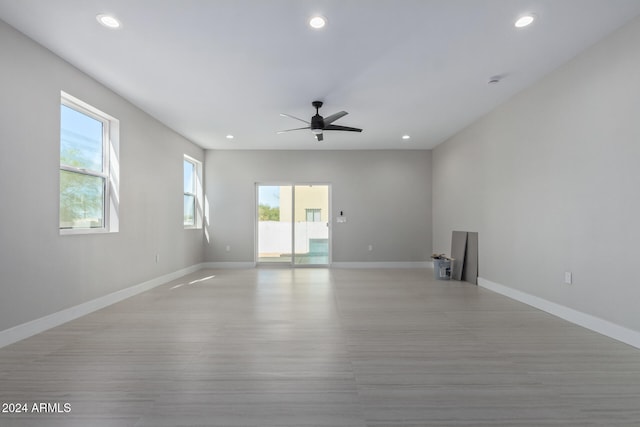 empty room featuring ceiling fan, a wealth of natural light, and light hardwood / wood-style floors