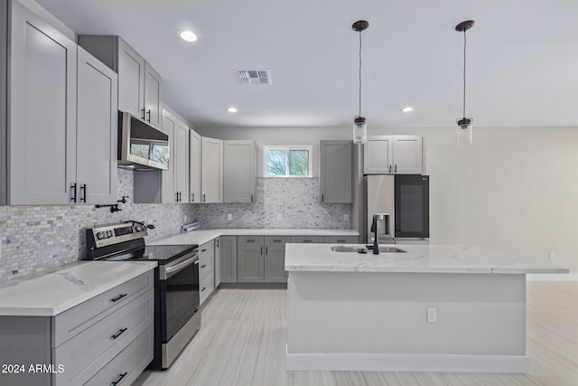 kitchen featuring gray cabinetry, appliances with stainless steel finishes, sink, hanging light fixtures, and a kitchen island with sink