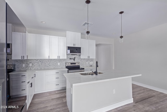 kitchen with appliances with stainless steel finishes, white cabinetry, a kitchen island with sink, pendant lighting, and sink