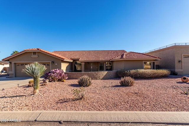 view of front facade featuring a tile roof, driveway, an attached garage, and stucco siding