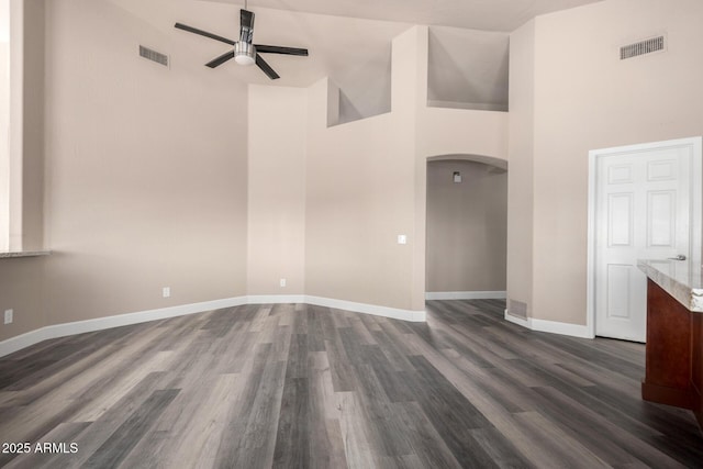 spare room with arched walkways, ceiling fan, dark wood-type flooring, and visible vents