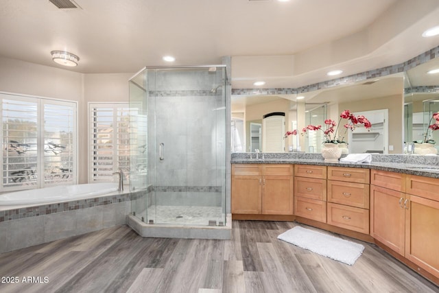 bathroom with a garden tub, double vanity, wood finished floors, and a shower stall