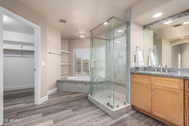 bathroom with visible vents, a spacious closet, and wood finished floors