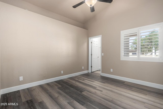 spare room with dark wood-style floors, lofted ceiling, baseboards, and a ceiling fan