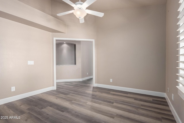 empty room featuring dark wood-style floors, a ceiling fan, and baseboards