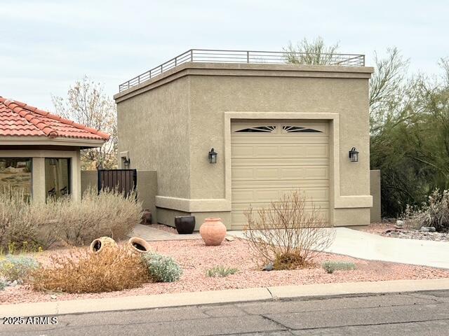 exterior space with a garage, concrete driveway, a tile roof, an outbuilding, and stucco siding