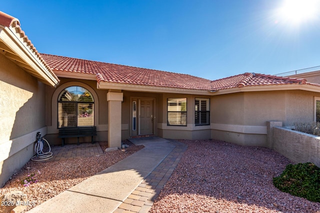 entrance to property with a tiled roof and stucco siding