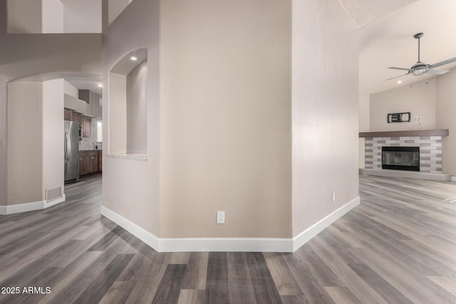 corridor with arched walkways, wood finished floors, visible vents, and baseboards