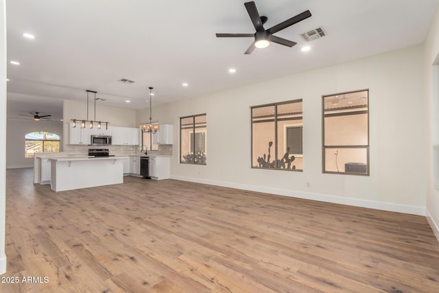 unfurnished living room featuring light hardwood / wood-style flooring, ceiling fan, and sink