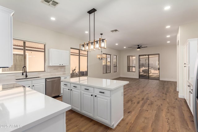 kitchen featuring white cabinetry, sink, stainless steel dishwasher, a kitchen island, and ceiling fan with notable chandelier