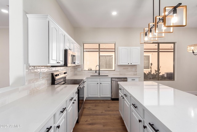 kitchen with pendant lighting, backsplash, white cabinets, sink, and stainless steel appliances