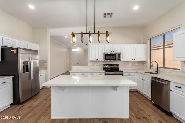 kitchen with pendant lighting, a center island, sink, and appliances with stainless steel finishes