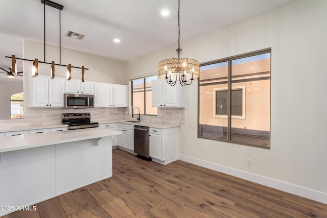 kitchen with stainless steel appliances, dark hardwood / wood-style flooring, decorative light fixtures, decorative backsplash, and white cabinets