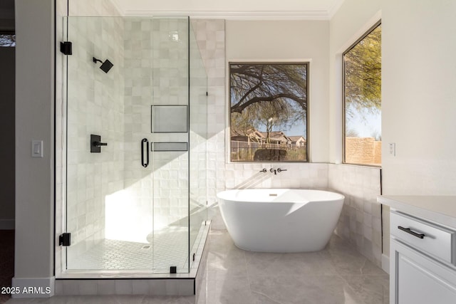 bathroom with ornamental molding, vanity, tile walls, and independent shower and bath