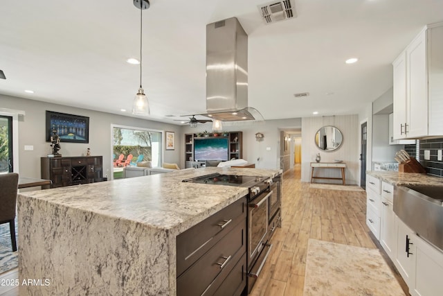 8730 E Montecito Ave, Scottsdale, AZ 85251 - kitchen featuring white cabinets, a center island, open floor plan, island range hood, and high end stainless steel range oven