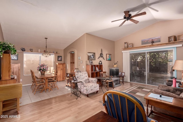 living room with light hardwood / wood-style flooring, ceiling fan with notable chandelier, and vaulted ceiling