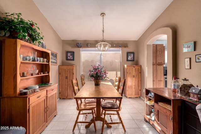 tiled dining space with vaulted ceiling and a chandelier